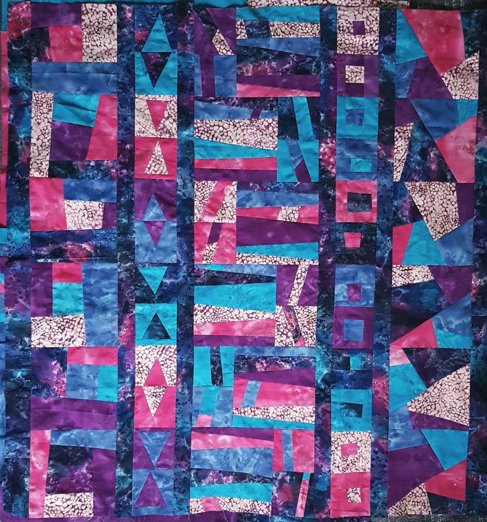 vibrant improv quilt top in purples, blues, pinks and blacks