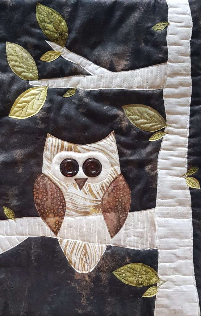 raw edge applique design featuring an owl in a tree against a dark background with a crescent moon in the sky